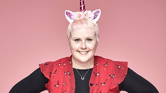 Becca, a wip supporter smiles in-front of a pink background 