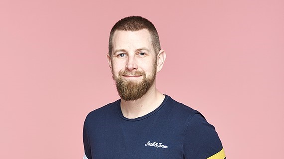 Rich, a wip supporter smiles in-front of a pink background 